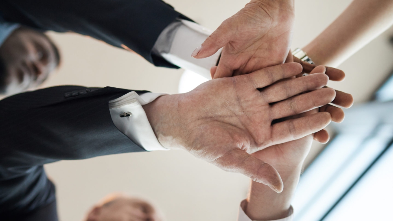 Close-up of business people standing in circle and holding hands they supporting each other during team work